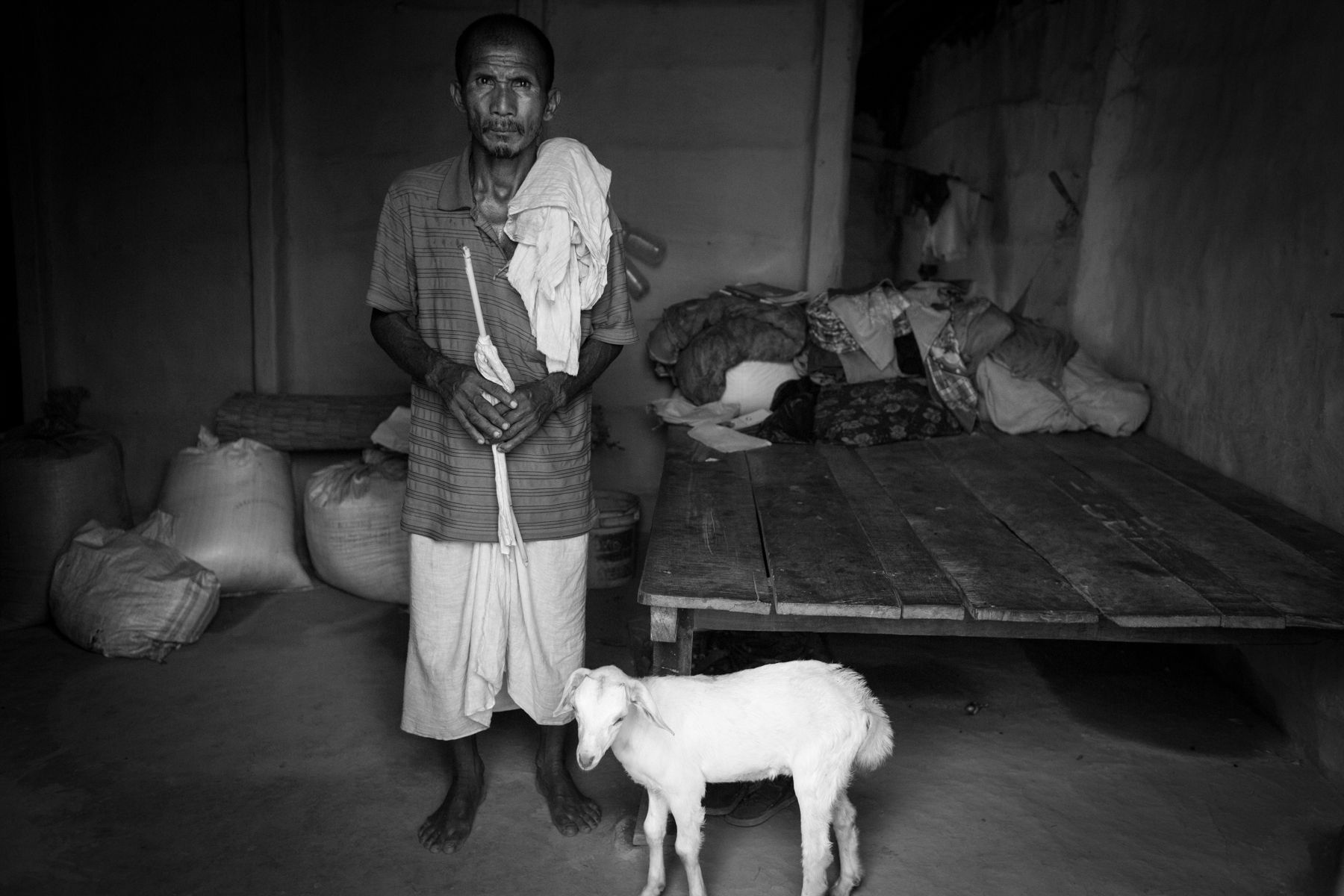 Bhagan Chaudhary, the husband of the late Parvati Devi, stands near their bed, out of which she was forcefully dragged. 24 August 2013, Supauli, Parsa, Nepal.